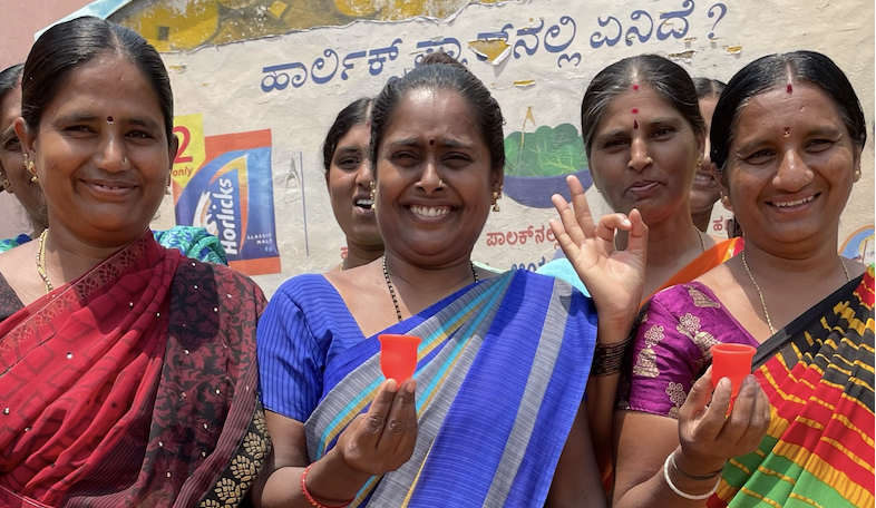 A group of women holding Asan menstrual cups and smiling at the camera